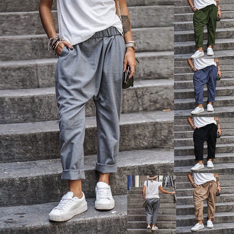 High-waist elastic harem trousers in grey, worn by a model on stone steps, front view with rolled cuffs and side pockets