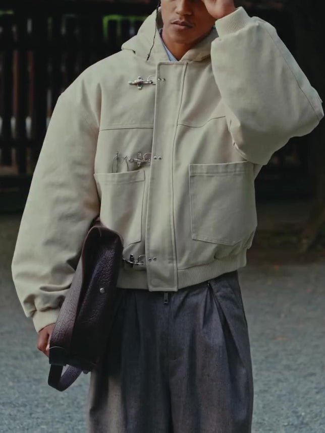 Model in the beige jacket with a dark bag under the arm, showing the wide sleeve