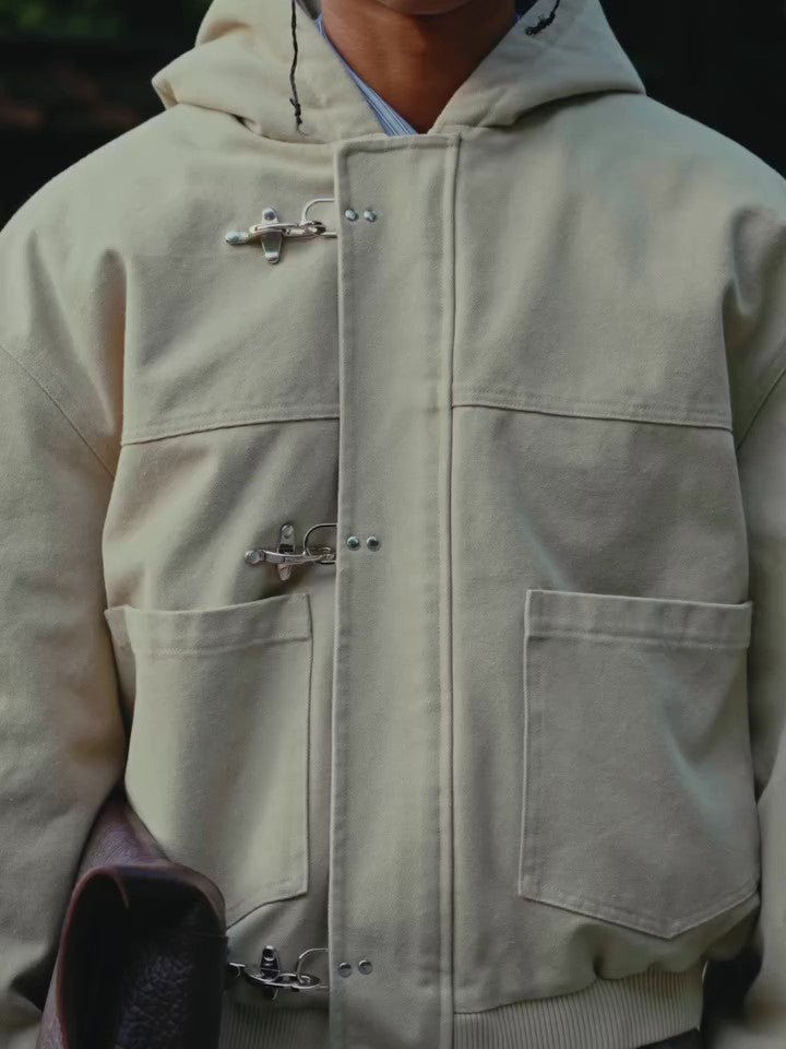 Close-up of the front: silver-coloured hook clasps on a placket and two patch pockets at the hip