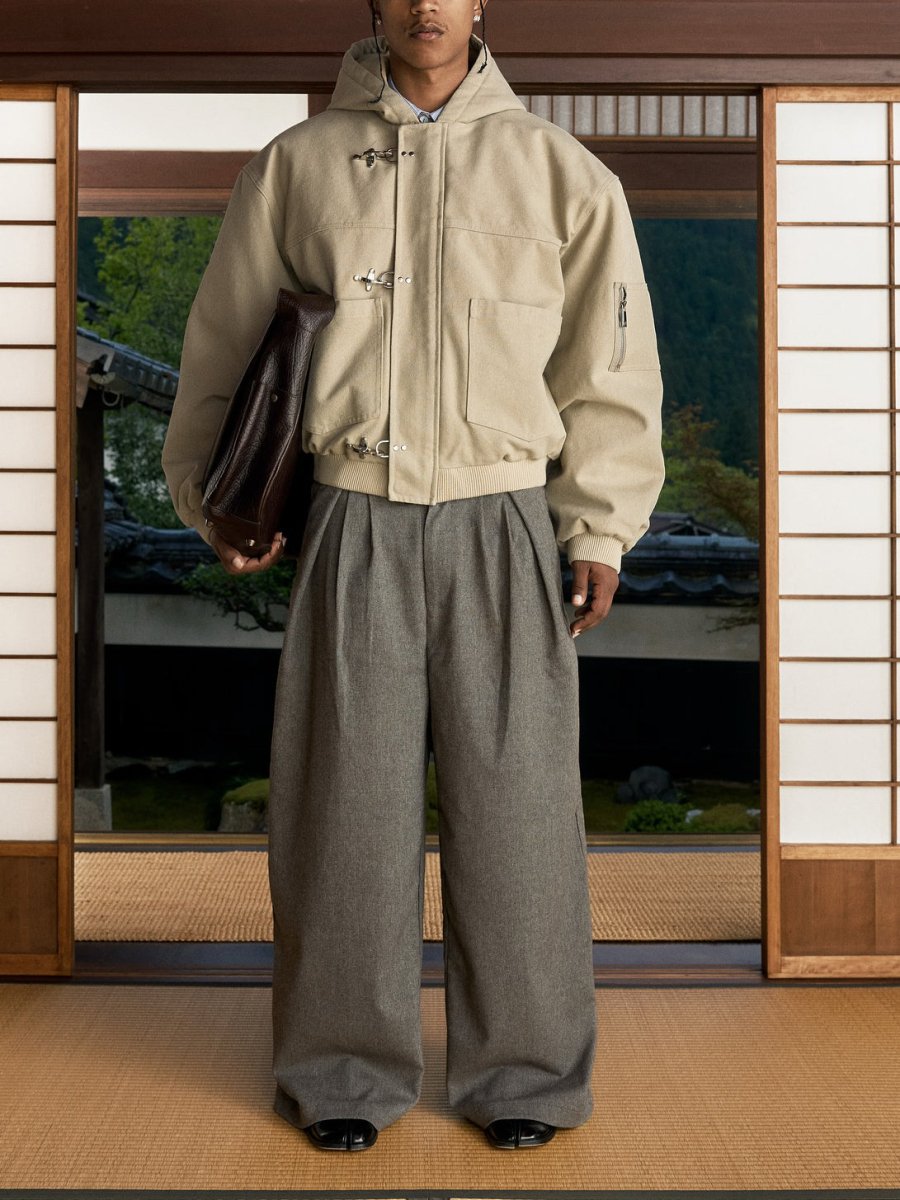 Full-length view of the beige jacket over wide grey trousers in a doorway