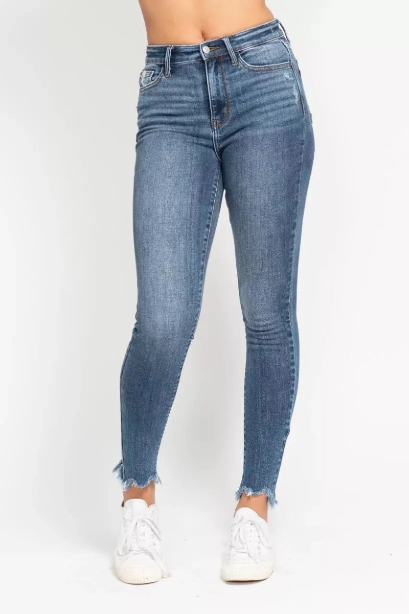 Blue high-waist skinny jeans with destroyed detailing and shark bit hem on model