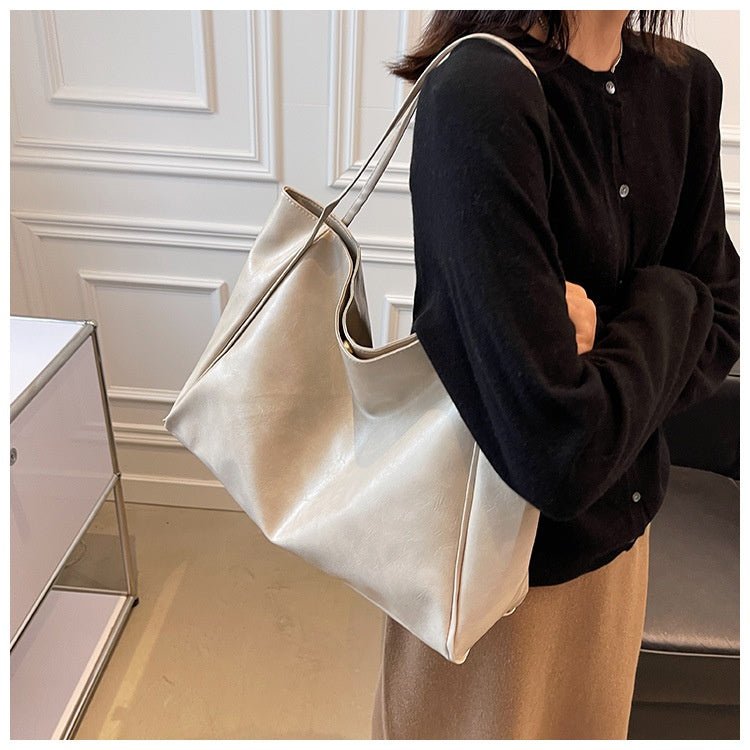 Off-white tote bag on the shoulder of a person in a black cardigan