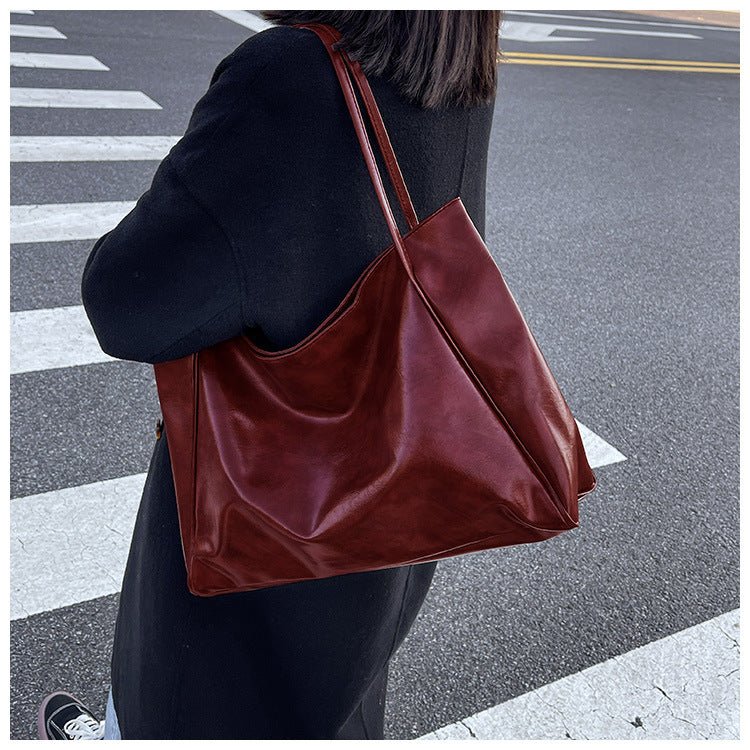 Dark red tote bag worn on the shoulder on a zebra crossing
