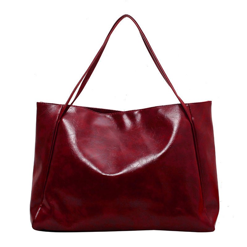 Dark red faux leather tote bag with two long straps on a white background