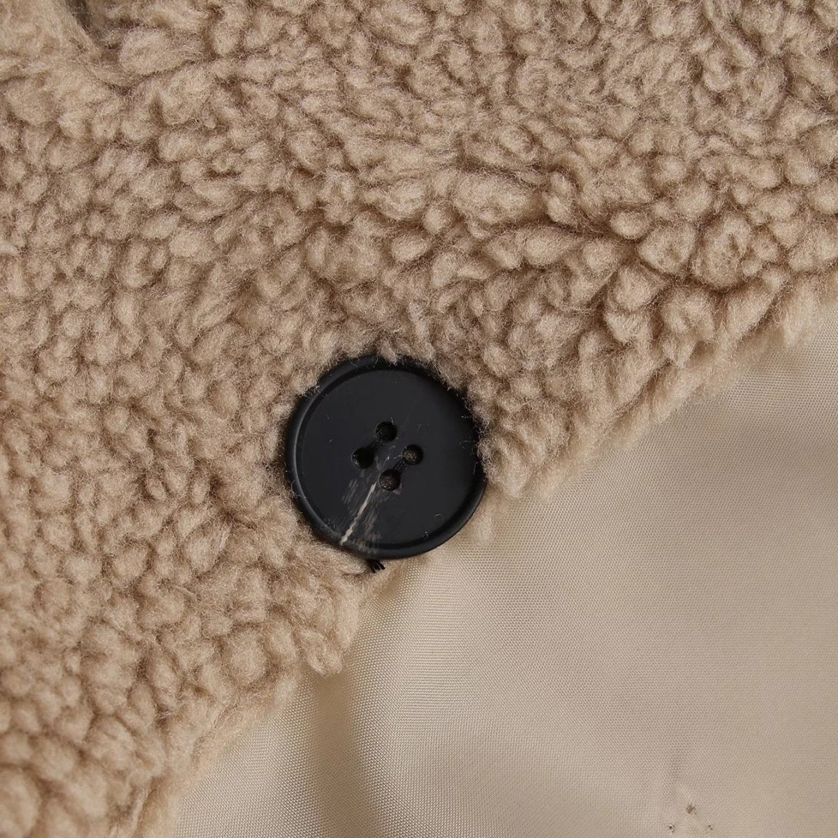Close-up of the black four-hole button on the teddy fleece