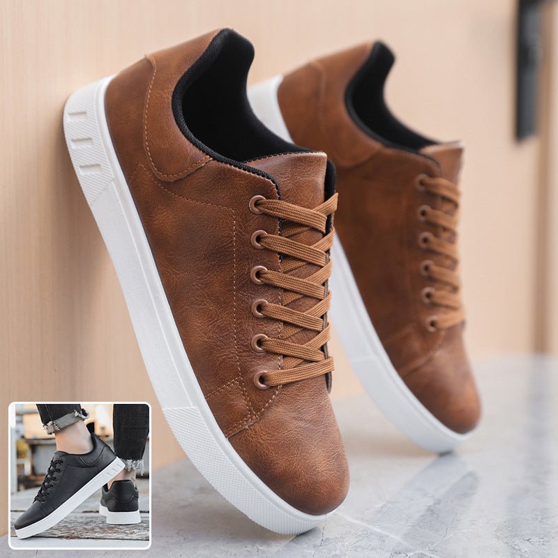 Bruine sneakers heren met witte zool tegen een muur, met een klein inzetje van het zwarte paar