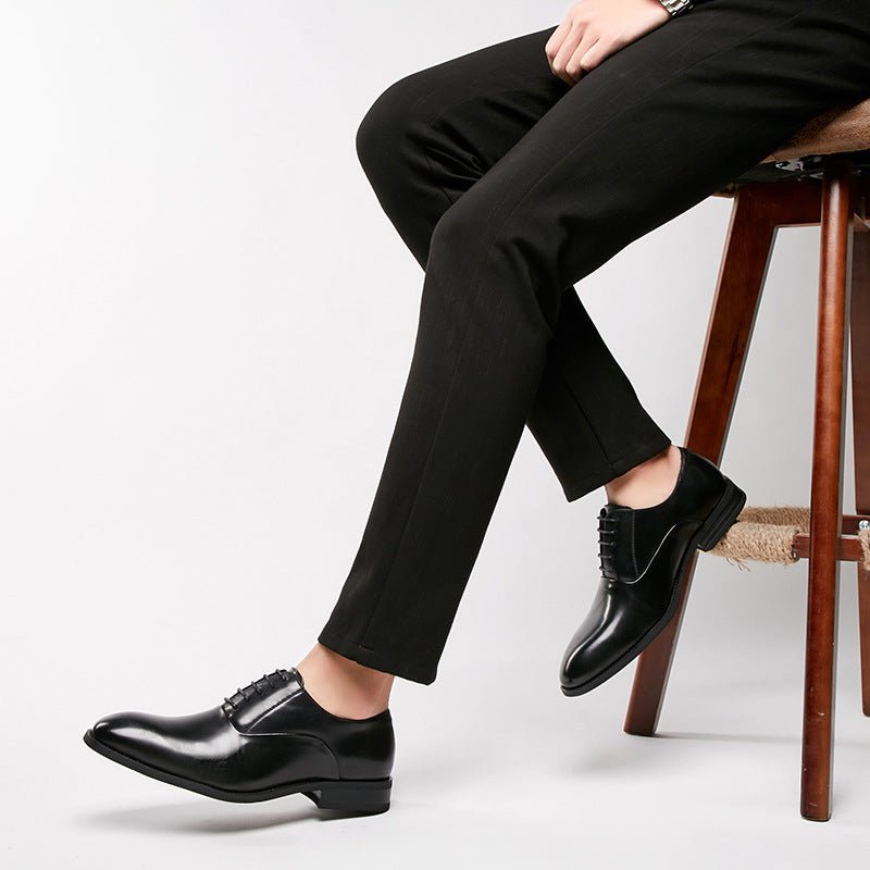 Man on a stool wearing the black lace-up shoes with slim black trousers