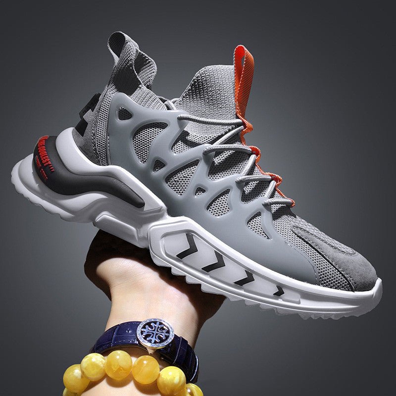 Grey knit sock-fit sneaker with lace cage, orange pull loop and chunky white sole, held in a hand