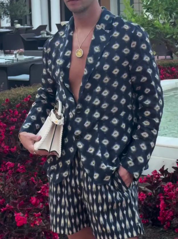Navy men's co-ord set: printed shirt-jacket worn open and matching shorts, by a pool with red flowers