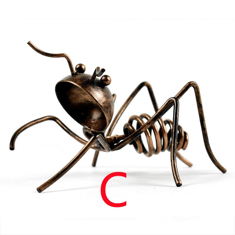 Bronze-coloured metal ant in pose C, crouching with its head tilted, marked with a red letter C