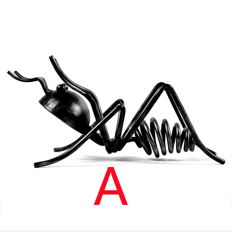 Black metal ant wine bottle holder in pose A, lying low with its legs spread, marked with a red letter A