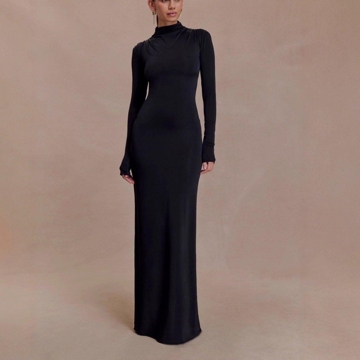Front view of the black maxi dress against a beige studio backdrop