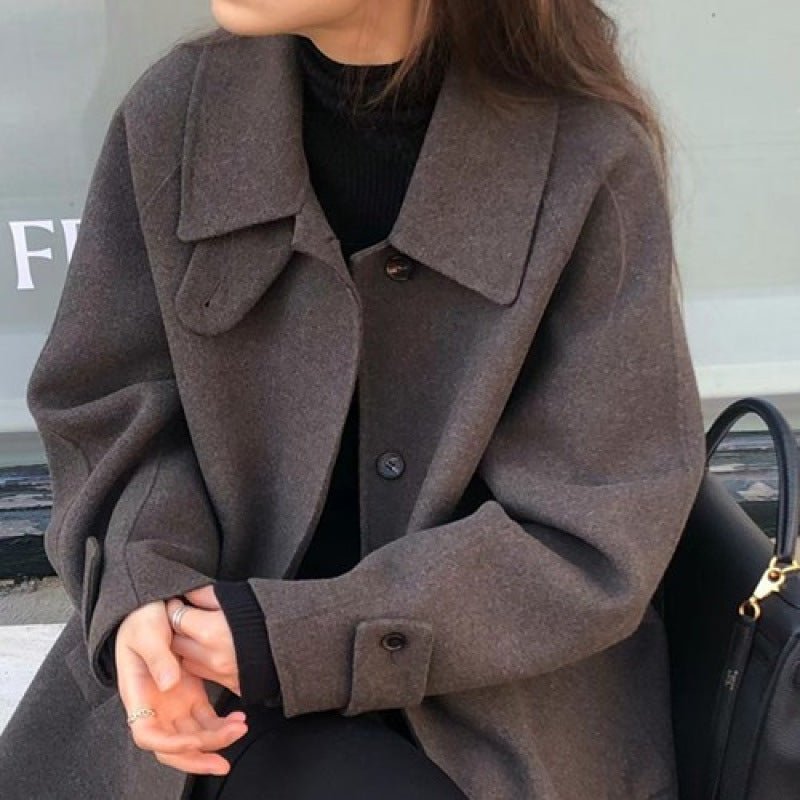 Dark brown coat close up: wide collar with a small tab, dark buttons and a buttoned cuff strap