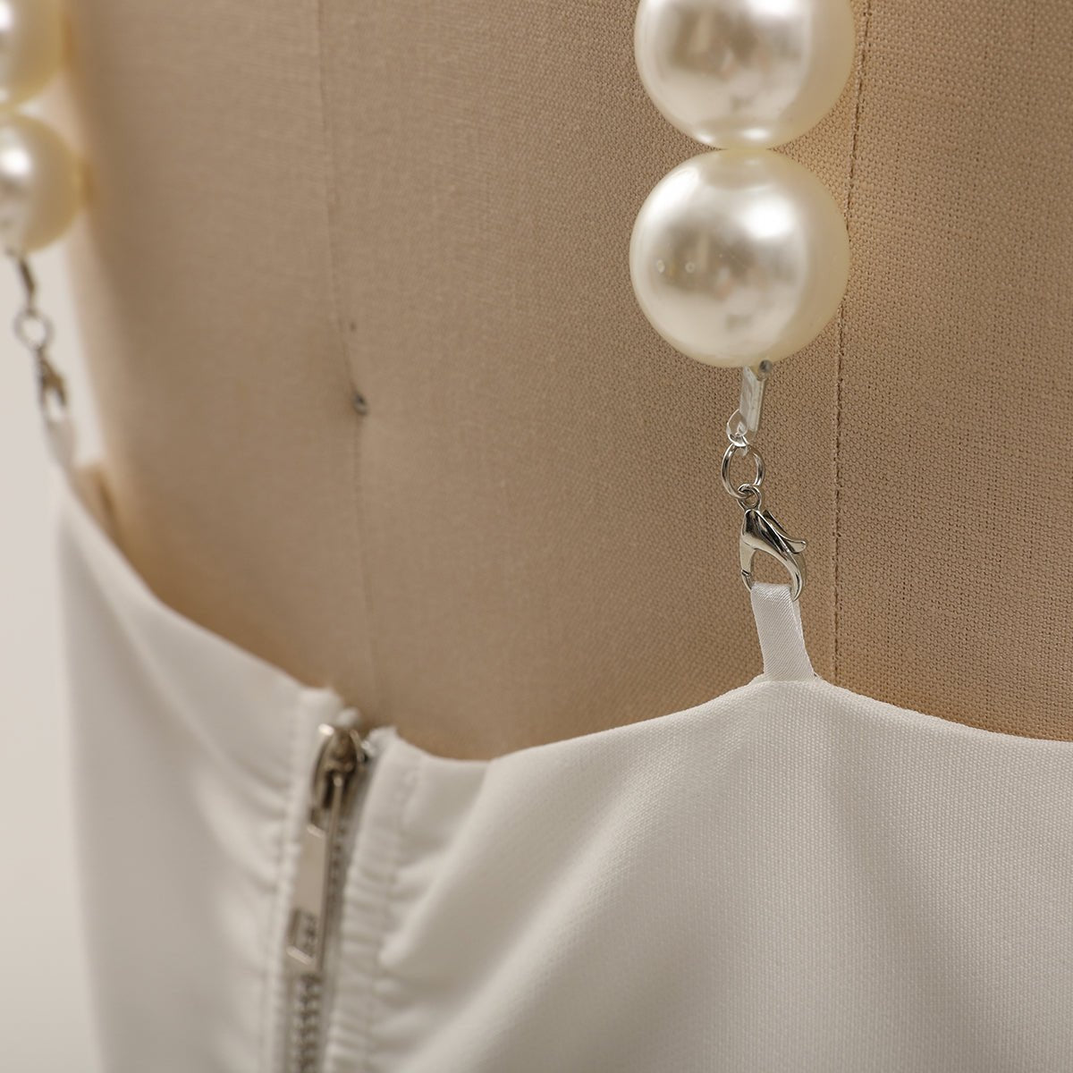 Detail of a lobster clasp hooking the bead strap onto the top, zip visible