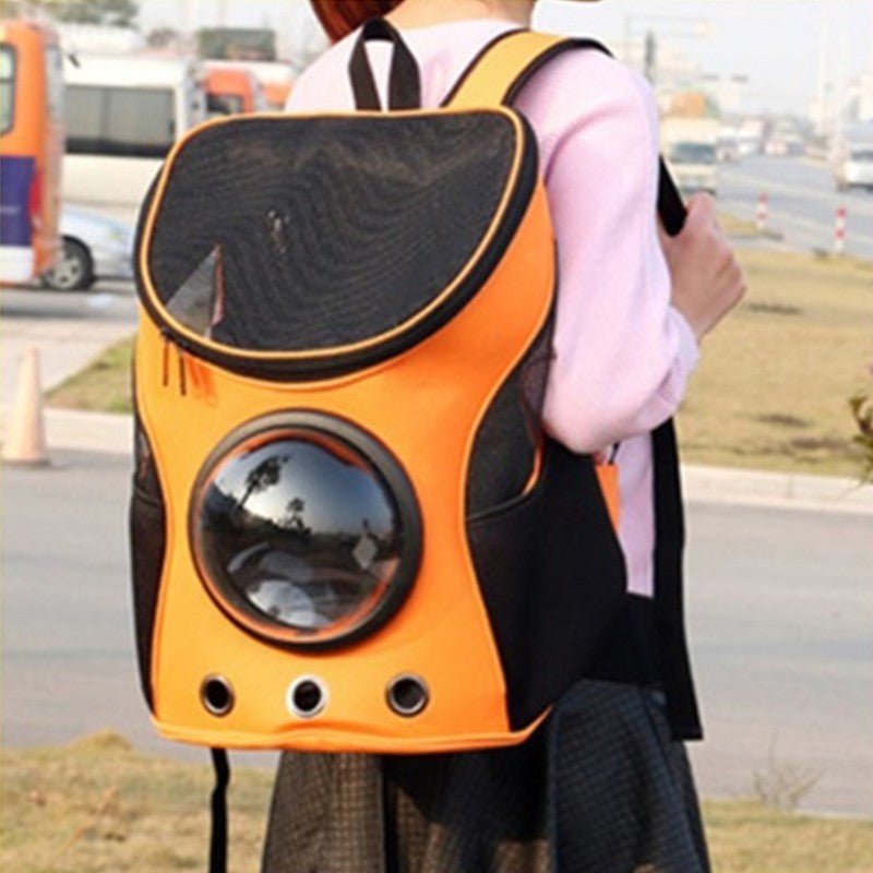 Orange pet carrier backpack with bubble window worn by a person in a pink top