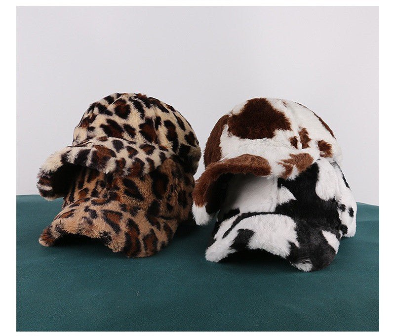 Leopard, brown cow and black-and-white cow caps stacked on a green table