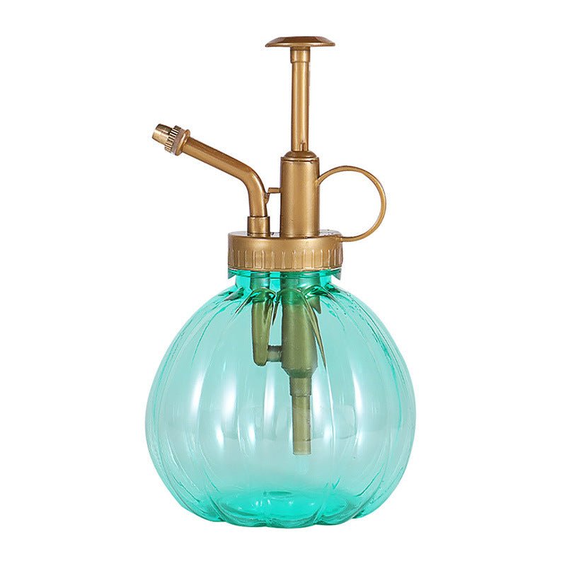 Groene plantenspuit fles in pompoenvorm met bronskleurige pomp, schuine tuit en vingerring op een witte achtergrond