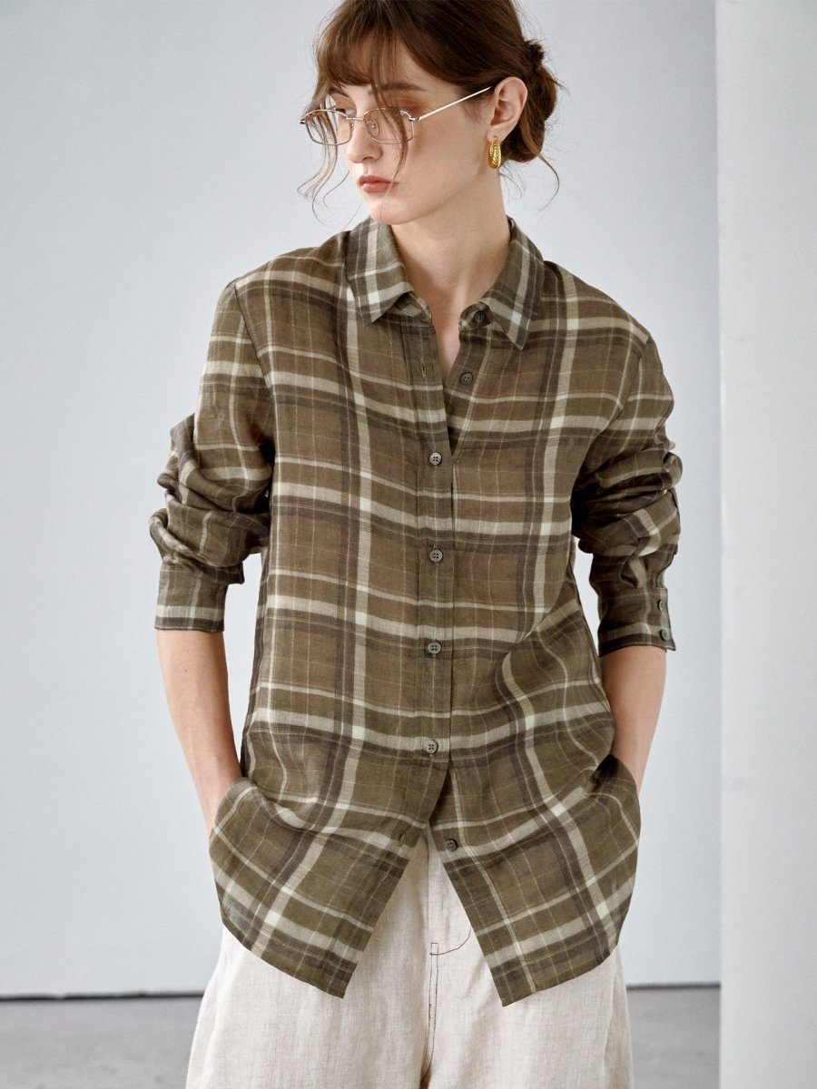 Model in an olive brown ramie check shirt worn untucked over cream trousers, hands in pockets