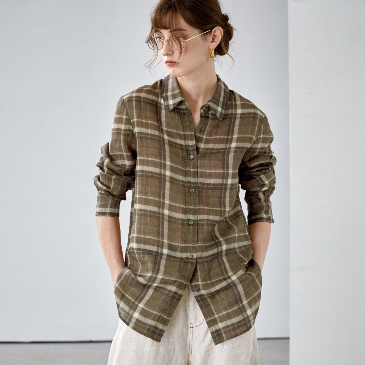 Three-quarter front view of the olive brown ramie check shirt, one hand in a trouser pocket