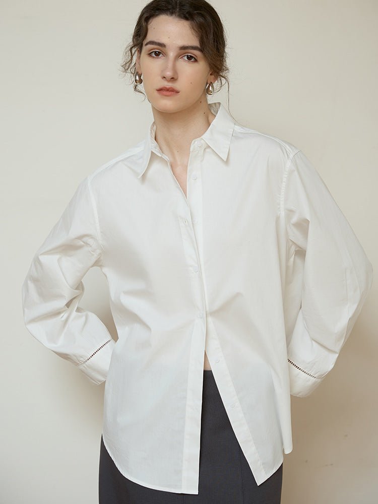 White relaxed long-sleeve shirt with pointed collar, worn open over dark trousers