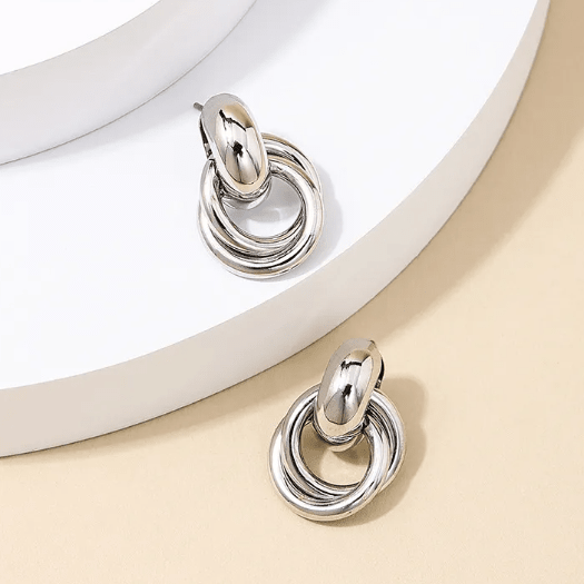Zilverkleurige oorbellen met dubbele ring op een crème en witte achtergrond