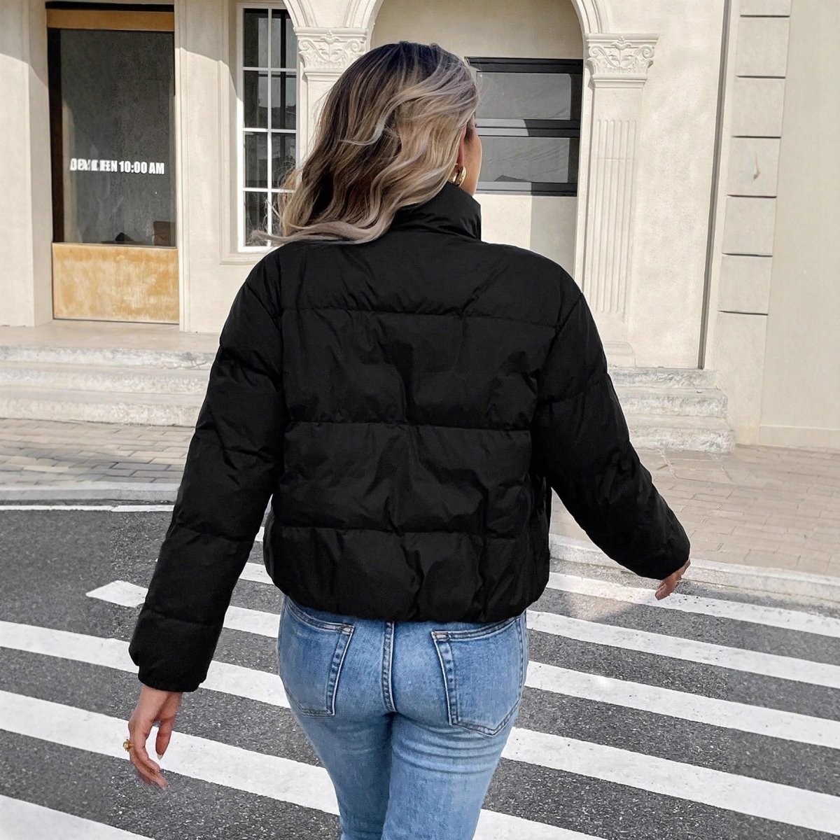 Back view of the black quilted puffer jacket with stand collar, ending at the waist