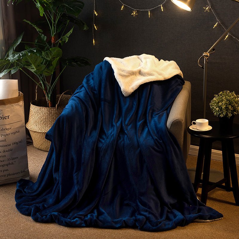 Reversible sherpa throw blanket in navy flannel with cream sherpa reverse, draped over an armchair