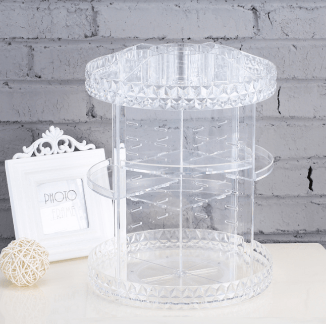 Empty clear rotating makeup organiser with diamond-pattern trays next to a white photo frame