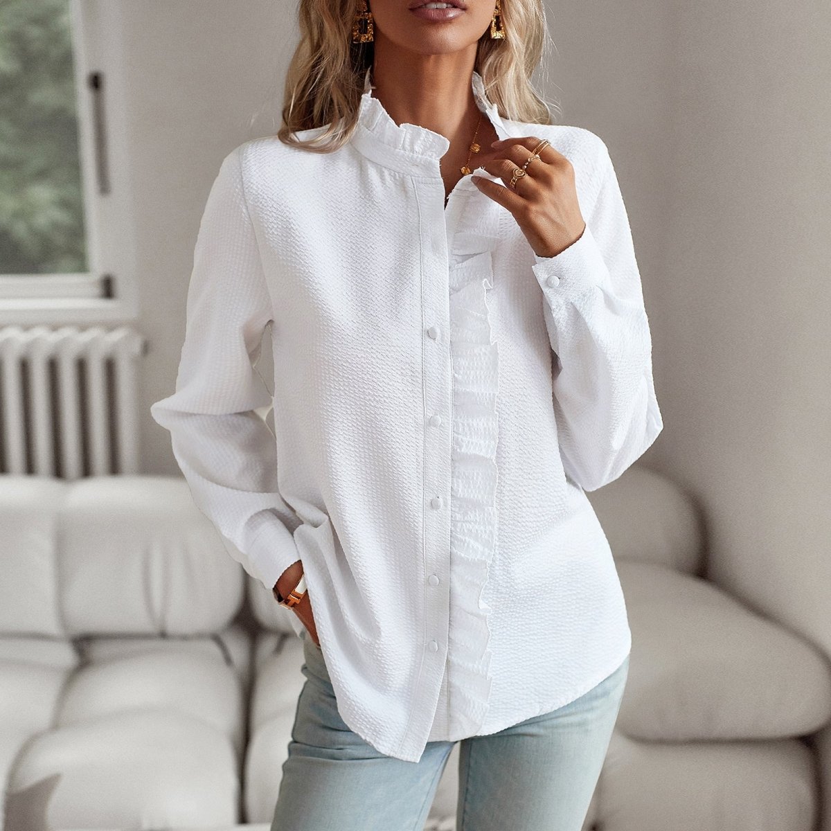 White blouse with ruffled collar worn loose, hand in pocket