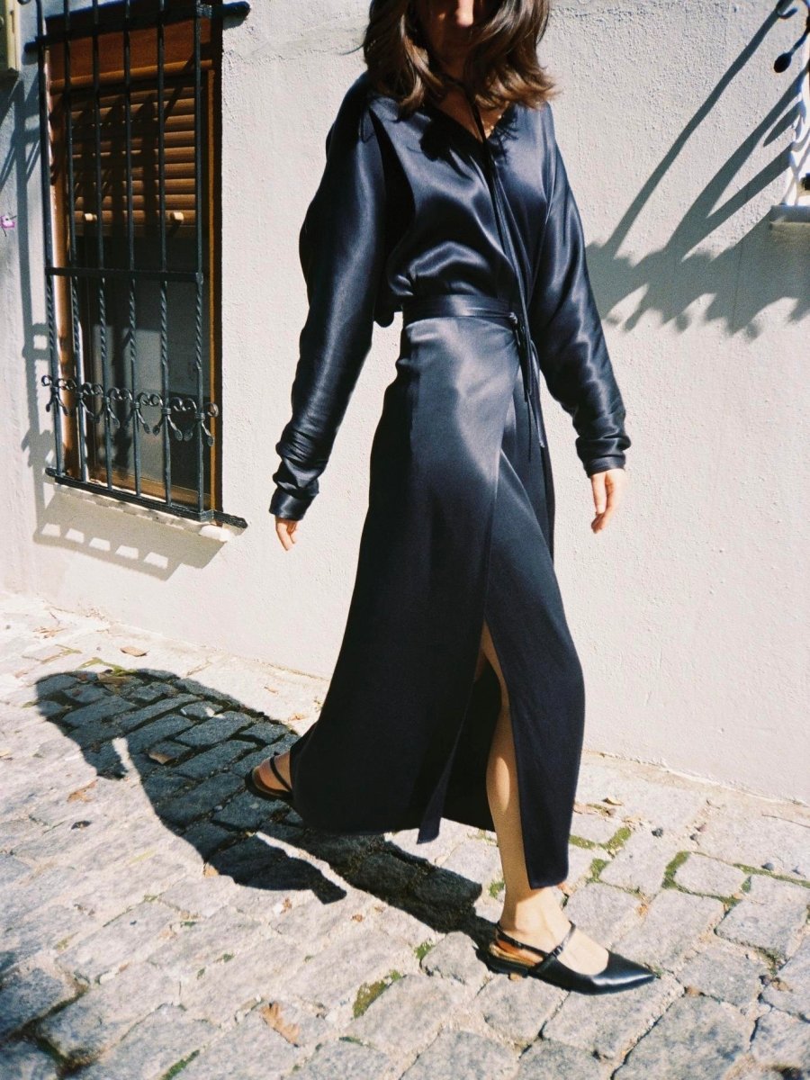 Navy satin-look dress in motion on a cobbled street, slit open
