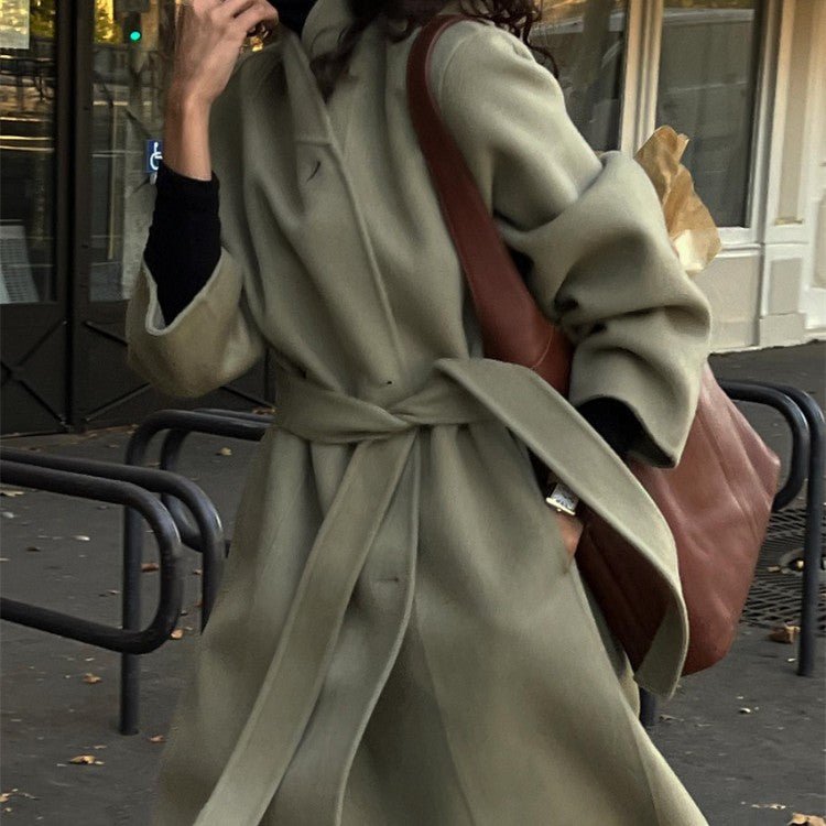 Khaki green wrap coat with the tie belt knotted at the waist, worn with a brown shoulder bag