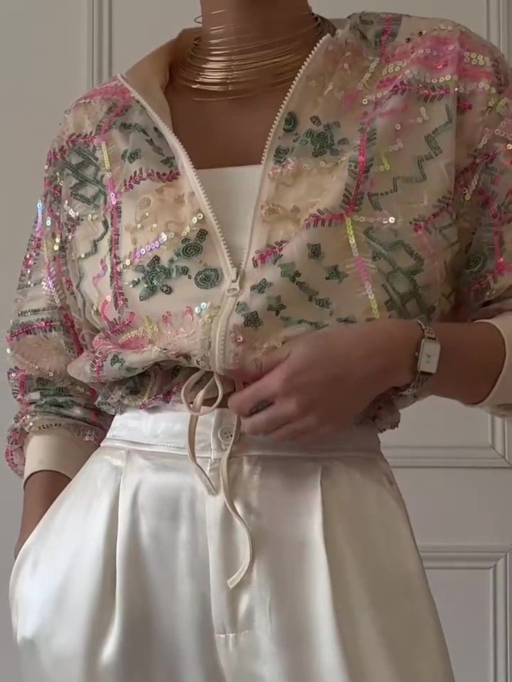 Sequin jacket half open over a white top, drawstring hanging at the hem