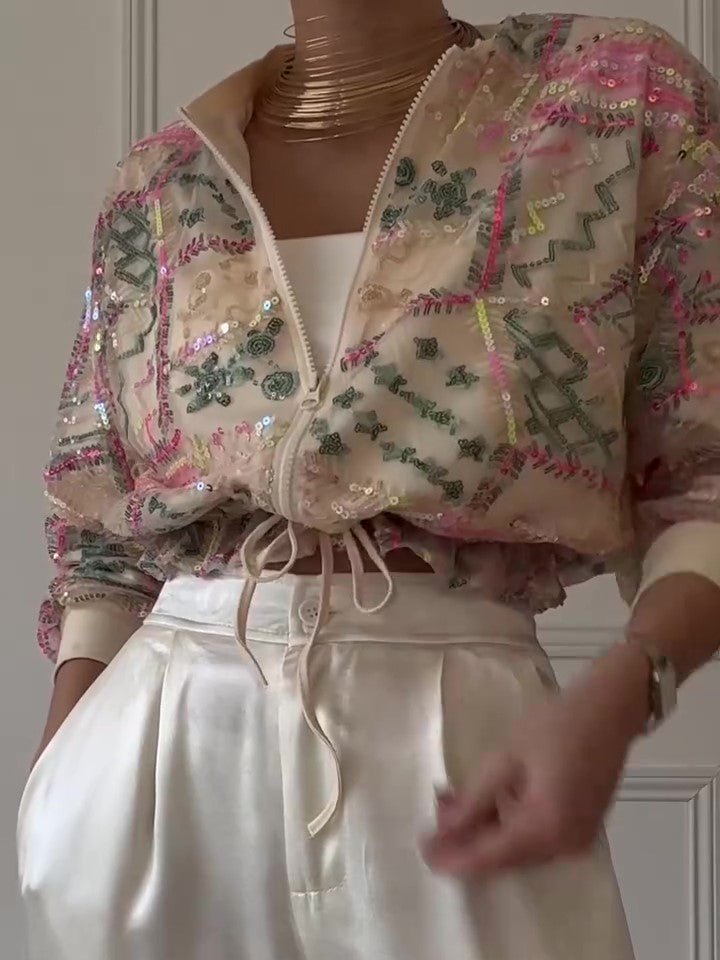 Cropped sequin jacket worn with cream wide trousers and gold-tone necklaces