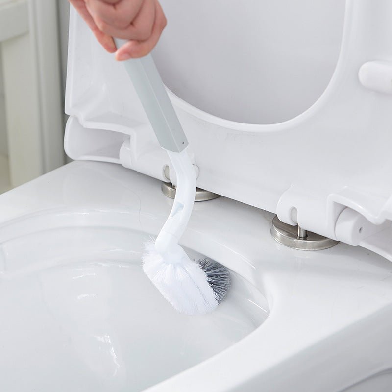 Hand cleaning a toilet bowl with the white brush with a curved neck