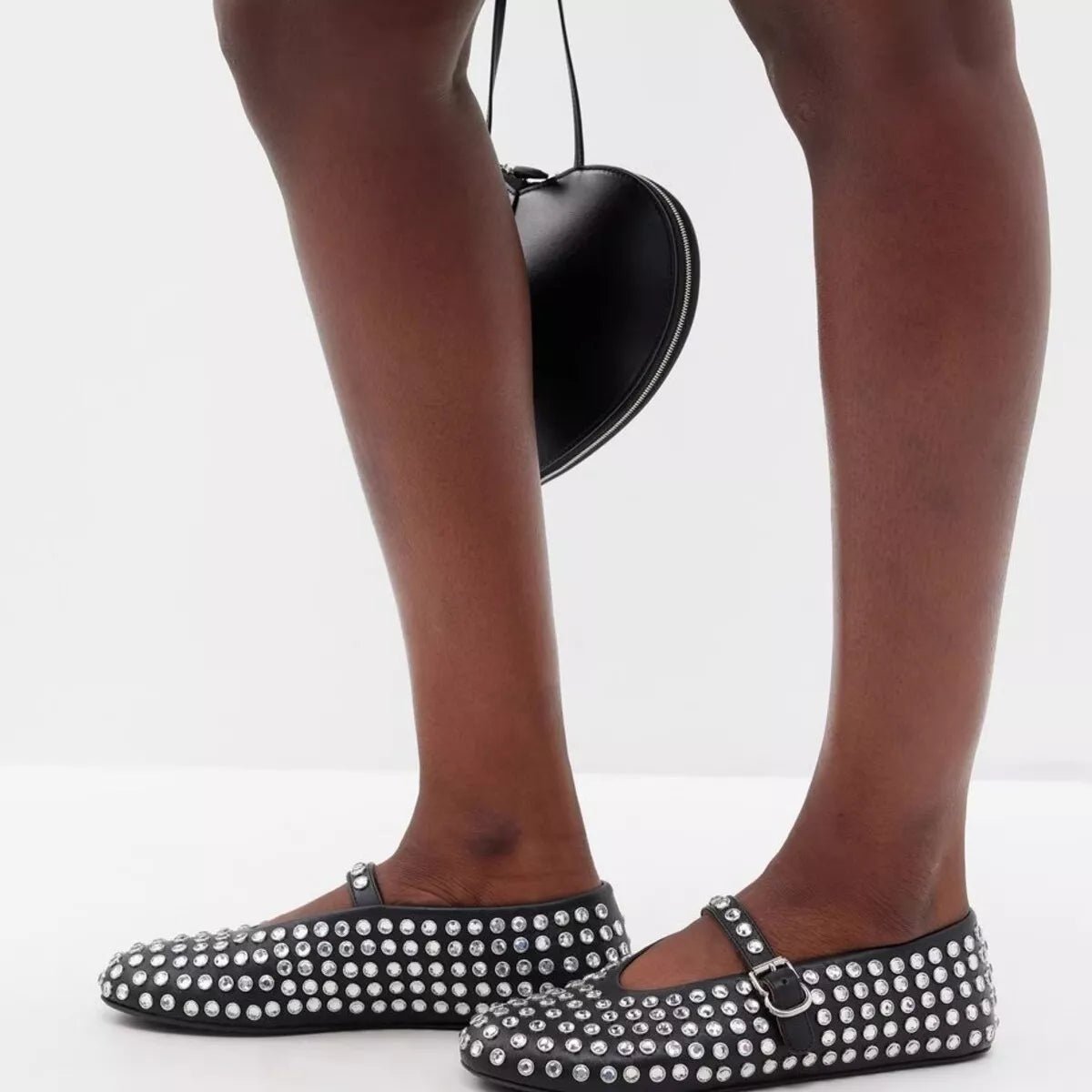 Black studded round toe slip-on flats with metallic accents on a white background