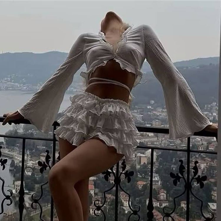 White two-piece set with arms spread, showing the wide bell sleeves