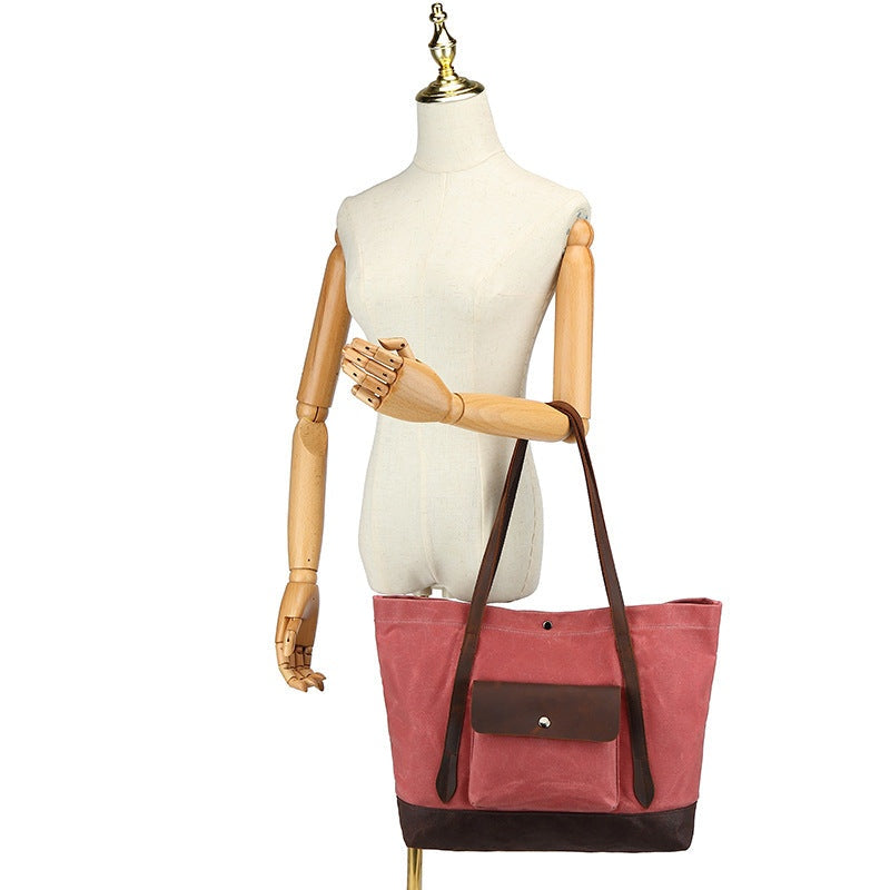 Rose rode waxed canvas tas hangend aan een mannequin voor maatreferentie