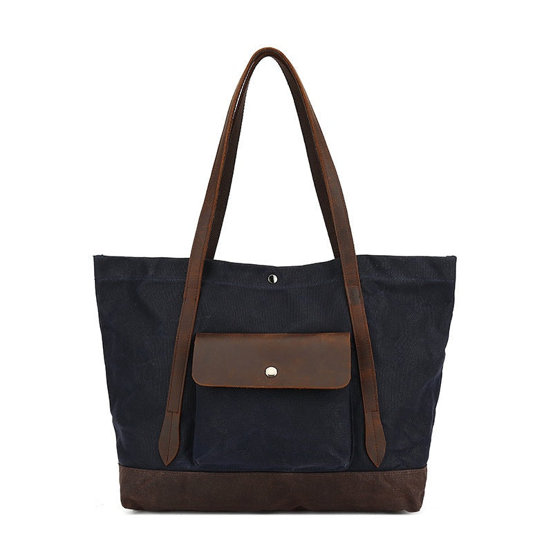 Zwarte waxed canvas tas met bruine leren details, vooraanzicht