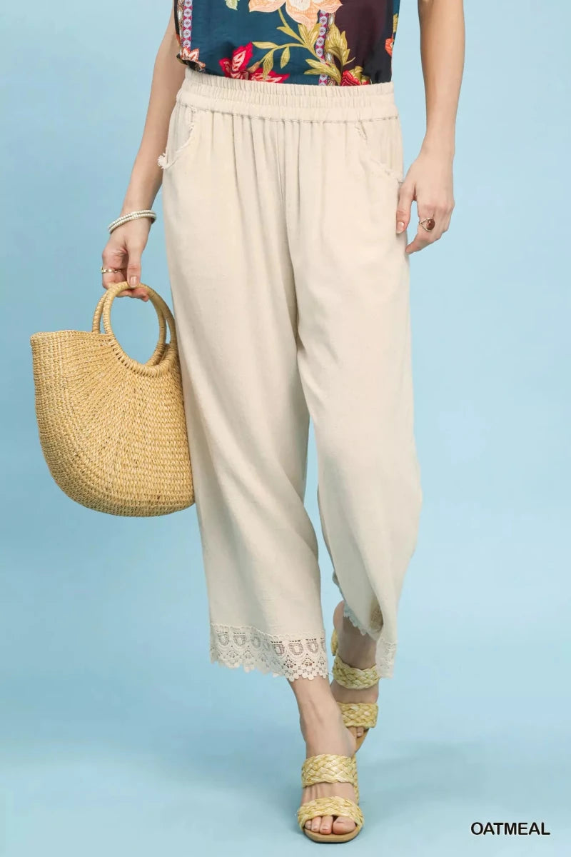 Model wearing Umgee linen wide leg cropped pants with lace trim in beige, showcasing relaxed fit and elegant detailing