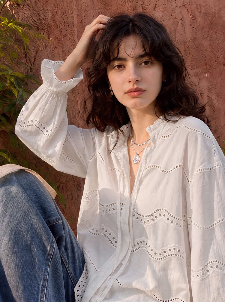 Model touching her hair, showing the ruffle cuff and stand collar of the off-white blouse
