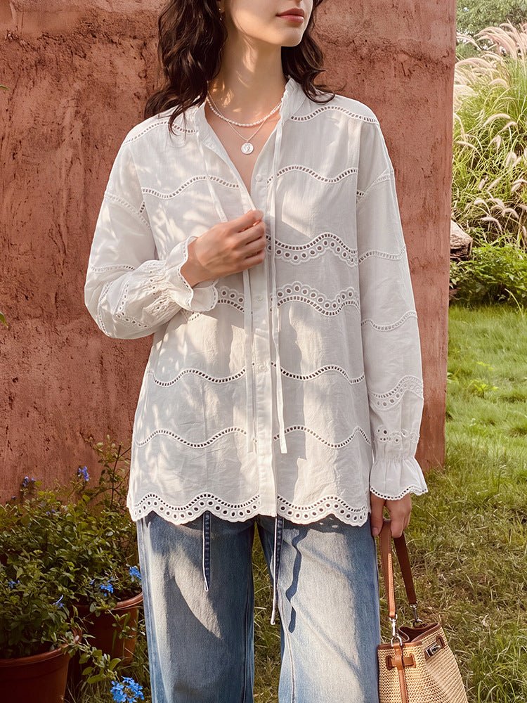 Front view of the off-white cotton blouse with eyelet embroidery, scalloped hem and ruffle cuffs